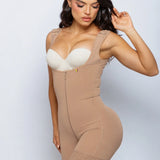A woman modeling a beige compression shapewear bodysuit with a built-in white bra, set against a plain light gray studio background.