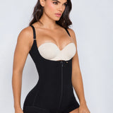 A woman modeling a black shapewear bodysuit with a front zipper and a contrasting beige underwire bra insert, set against a plain light gray studio background.