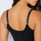 Close-up back view of a woman wearing a black shapewear bodysuit with adjustable shoulder straps and small silver metal hardware.