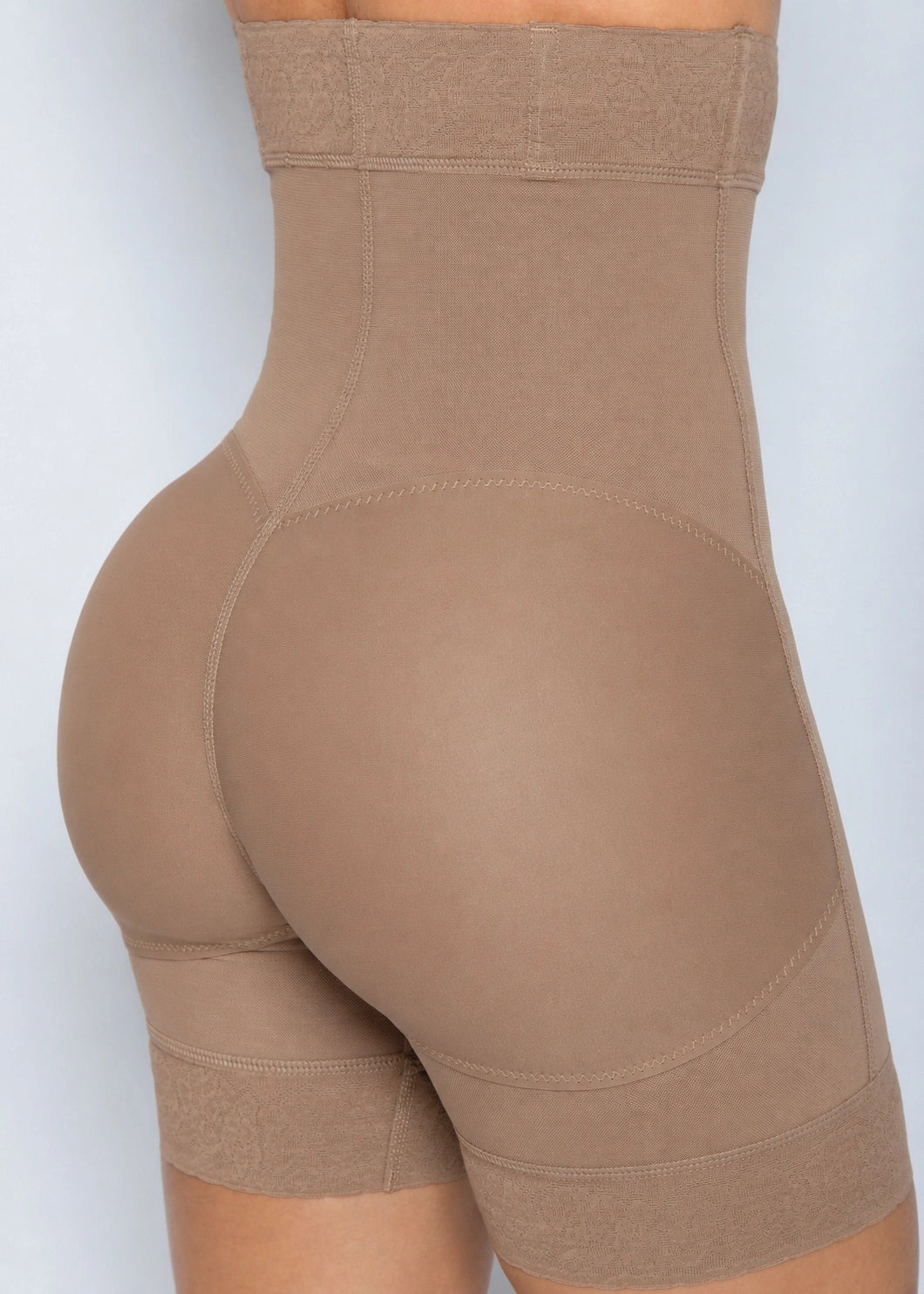 Close-up of a model wearing high-waisted shapewear shorts in a solid taupe-brown color, shown from a side-rear angle against a light gray background.