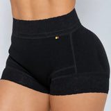 Black high-waisted compression or shapewear shorts with lace trim at the waistband and leg hems, shown on a model from the back against a light gray background.